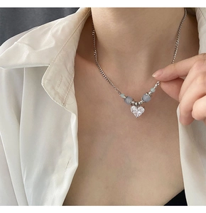 Détail du collier avec pendentif cœur et perles bleues sur la clavicule d'un mannequin