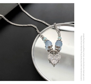 Détail du collier cœur en argent avec zircon transparent et perles bleu clair