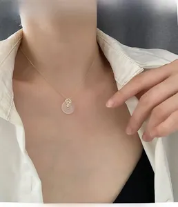 Gros plan d'un collier en bambou doré avec pendentif imitation jade sur un mannequin