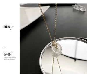 Détail du collier doré avec pendentif blanc et fermoir coeur brillant sur miroir