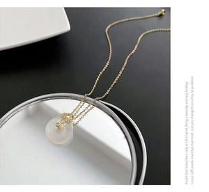 Détail du collier chaîne dorée avec pendentif anneau blanc et motif cœur sur miroir