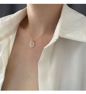 Détail du collier bambou doré avec pendentif en jade blanc porté par un mannequin chic
