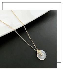 Gros plan du fermoir en cœur diamanti et pendentif jade rond sur collier en or