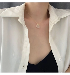 Gros plan d'un pendentif Ping'an en jade sur une chaîne dorée avec un col blanc