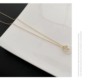 Détail du collier avec pendentif cœur en bambou et cercle de pierre blanche dorée