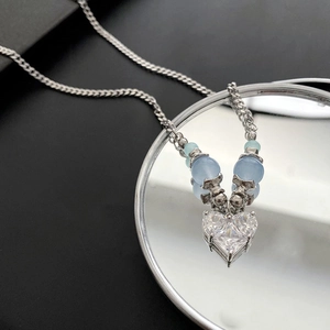 Collier argenté raffiné avec pendentif cœur en zircone et perles bleues sur miroir