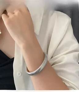 Close-up of a silver wide flexible spring cuff bracelet worn by a model in casual style