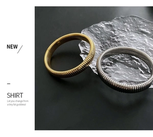 Detail of gold and silver textured cuff bracelets with ribbed spring-like patterns
