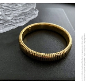 Detailed view of golden Tubogas texture on a wide stainless steel stretch bracelet