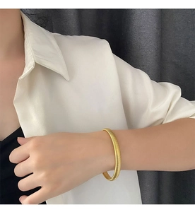 Detailed view of wide golden ribbed cuff bracelet with textured coil pattern on wrist
