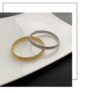 Close-up of gold and silver threaded elastic bangle set displayed on a ceramic tray
