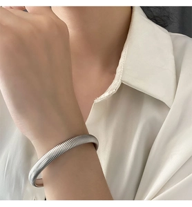Detail shot of silver wide textured titanium steel cuff bracelet on a white shirt sleeve