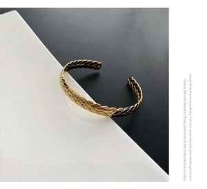 Close-up of golden open cuff bracelet featuring an intricate wheat ear textured pattern