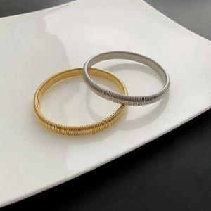 Chic gold and silver stretch metal spring bracelets displayed on a white tray