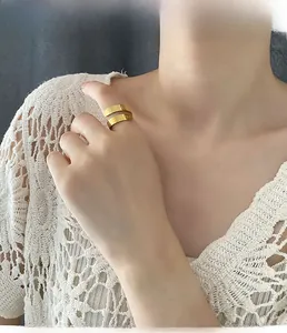 Close-up of golden open ring with letter engraving worn on finger for a chic style