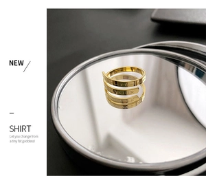 Detail of gold triple-spiral titanium ring with 'STRONGER' engraving and polished finish