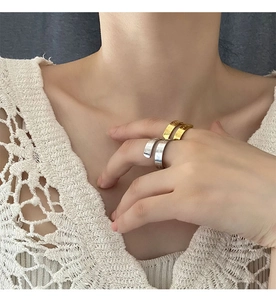 Close-up of gold and silver chunky engraved rings worn by a model in a soft setting