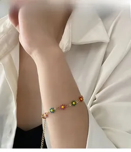 Close-up of a colorful daisy flower bracelet with a bright gold-plated chain on a wrist