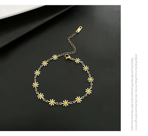 Detail of gold daisy bracelet featuring white enamel petals and adjustable lobster clasp