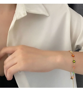 Close-up of colorful daisy flower charms on a gold adjustable chain bracelet