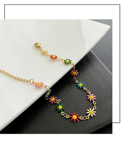 Close-up of colorful daisy charms on gold-plated chain necklace with lobster clasp