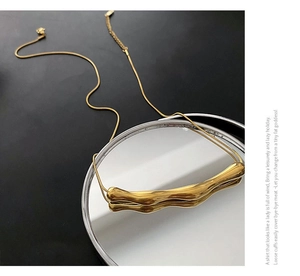 Dettaglio macro della collana dorata irregolare stile lava fluida su uno specchio