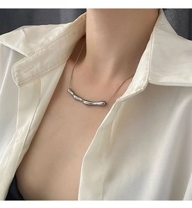 Dettaglio di una collana con ciondolo in stile lava d'argento su camicia bianca