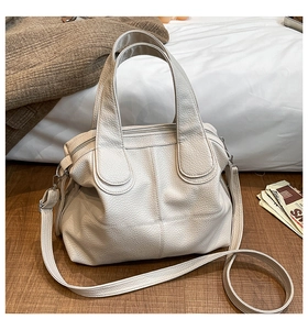 Detailed close-up of cream-colored tote bag with pebble leather texture and silver hardware