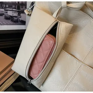 Detail of a beige tote bag featuring a small pink quilted coin purse with zipper