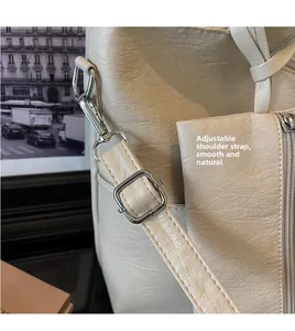 Detail of adjustable shoulder strap with silver metal buckle on creamy leather tote