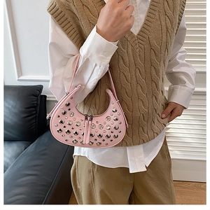 Detail of pink crescent bag with silver star rivets shown on a stylish model's shoulder