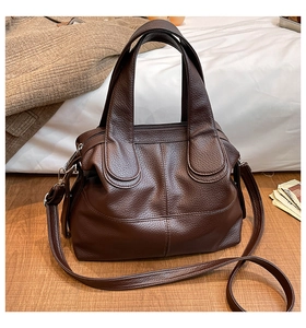 Detail of dark brown lychee grain leather handbag with saddle stitching and soft texture