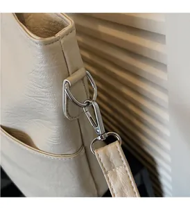 Detailed macro of silver metal hardware and lobster clasp on cream leather tote bag