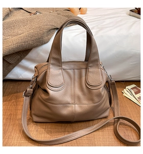 Detail of a large brown leather tote bag showing litchi texture and horseshoe stitching
