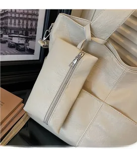 Close-up of cream PU leather tote bag with matching detachable zip pouch and silver hardware