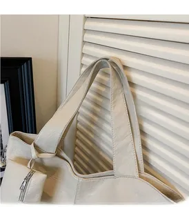 Detail of cream tote bag featuring reinforced handles and side zipper pocket