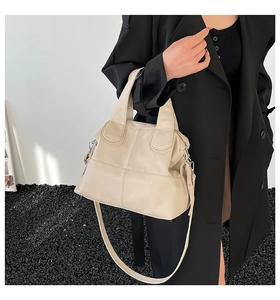 Creamy white lychee grain tote bag with adjustable shoulder strap held by model