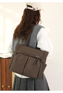 Detail van de donkerbruine draagtas met multi-zakontwerp en glanzend waterdicht nylon