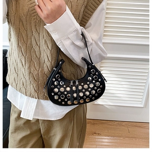 Detail of a black hobo bag with silver studs worn by a model in a modern style