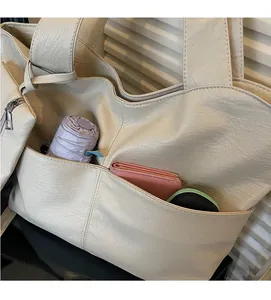 Detail view of large faux leather tote bag showing a practical front pocket with items
