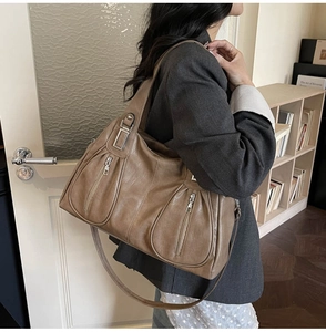 Detail of vintage brown leather tote bag showing multi-zipper pockets and silver hardware