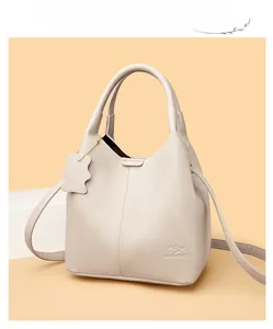 Détail de la texture cuir beige et logo kangourou sur un sac à main chic pour femme