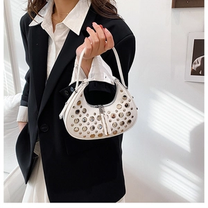 Close-up of white crescent rivet bag with silver metal studs and leather tassels