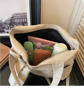 Top view of spacious interior of cream tote bag filled with tablet and daily essentials