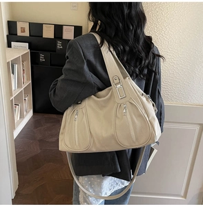 Detailed side view of beige leather tote bag featuring functional vertical zip pockets