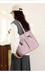 Detail van lichtroze nylon shopper met handige zakken over de schouder gedragen