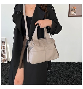 Detail of a large beige leather tote bag with crossbody strap and cross-stitch pattern