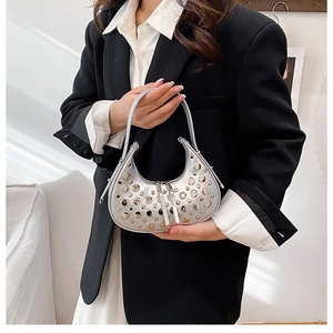 Model wearing a silver crescent rivet hobo bag with a black suit for a stylish modern look