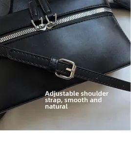 Detail of black leather bag with silver double zippers and adjustable strap