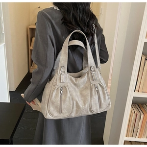 Close-up of light grey tote bag showing front zipper pockets and silver buckle details